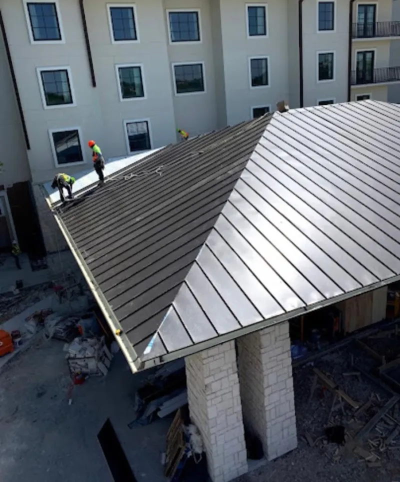 Crew installing standing seam metal roof panels on a commercial project in Cedar Mill
